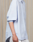 Tatiana Blouse in Sky showcasing a sophisticated shirt collar, concealed button placket, and romantic puff sleeves.