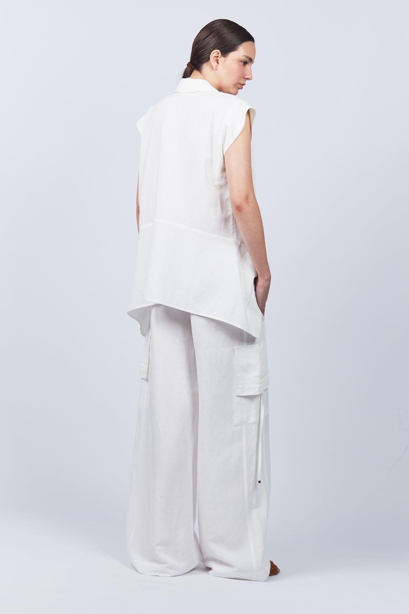 Zayla Blouse in Off White, elegant sleeveless blouse with an asymmetrical hem and shirt collar.