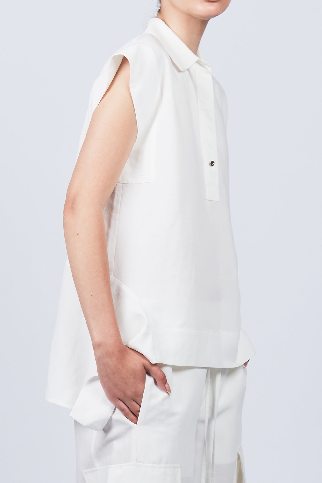 Zayla Blouse in Off White, elegant sleeveless blouse with an asymmetrical hem and shirt collar.