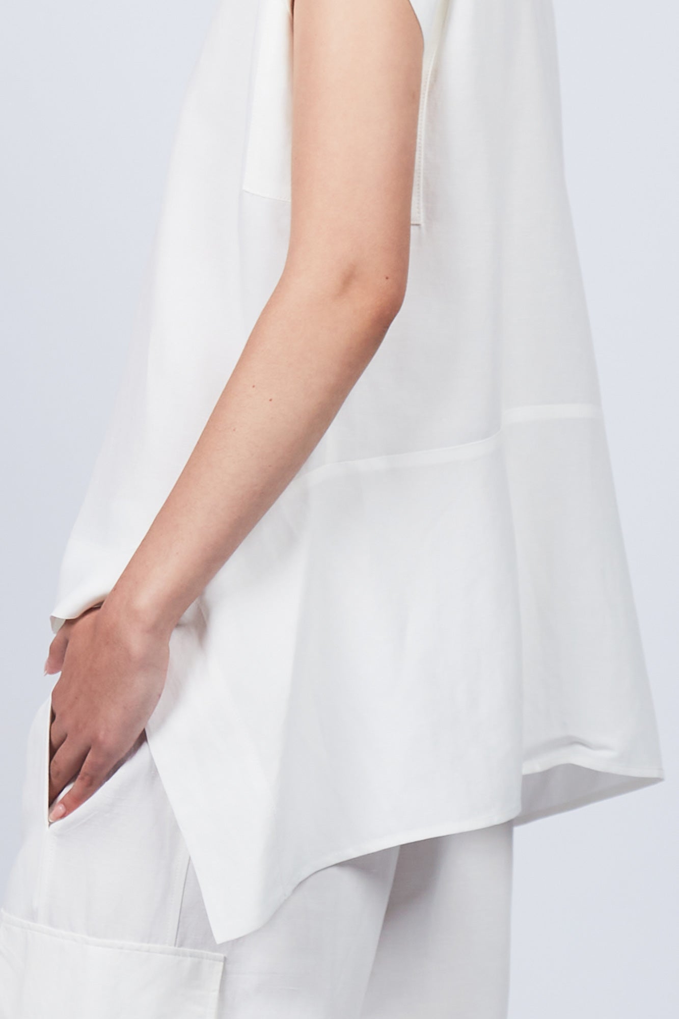 Zayla Blouse in Off White, elegant sleeveless blouse with an asymmetrical hem and shirt collar.